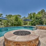 built in fire pit by swimming pool with tree line