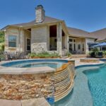 red stone hot tub surround next to large custom shaped pool