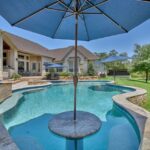 umbrella and cocktail table in wading area of swimming pool