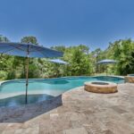 grey stone patio pavers next to countryside swimming pool with umbrellas