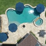 areal view of custom swimming pool with hot tub and firepit built into patio