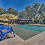 lounge chairs with umbrellas by rectangle swimming pool under oak trees